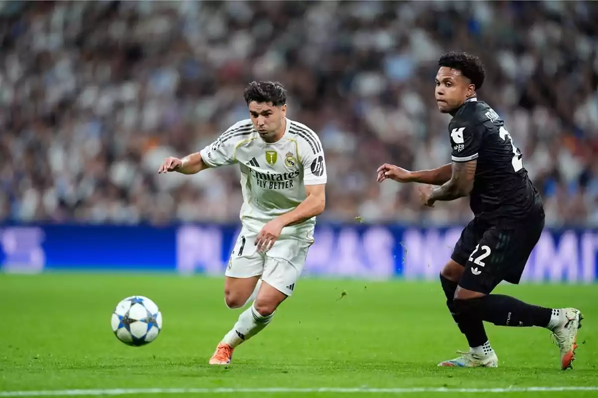 Dos futbolistes disputen la pilota durant un partit en un estadi ple d’espectadors