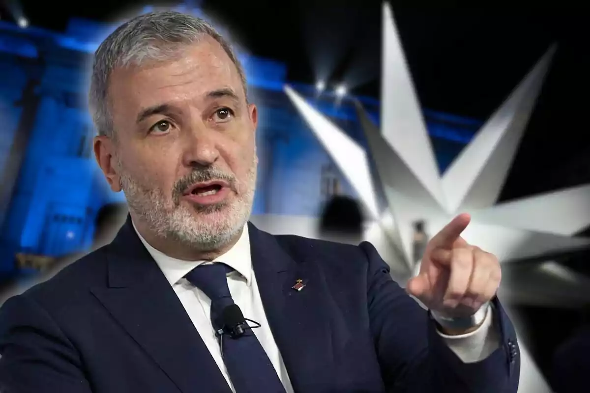 Hombre de cabello canoso y barba vestido con traje azul oscuro señalando con el dedo mientras habla, con una estructura moderna y luces azules de fondo