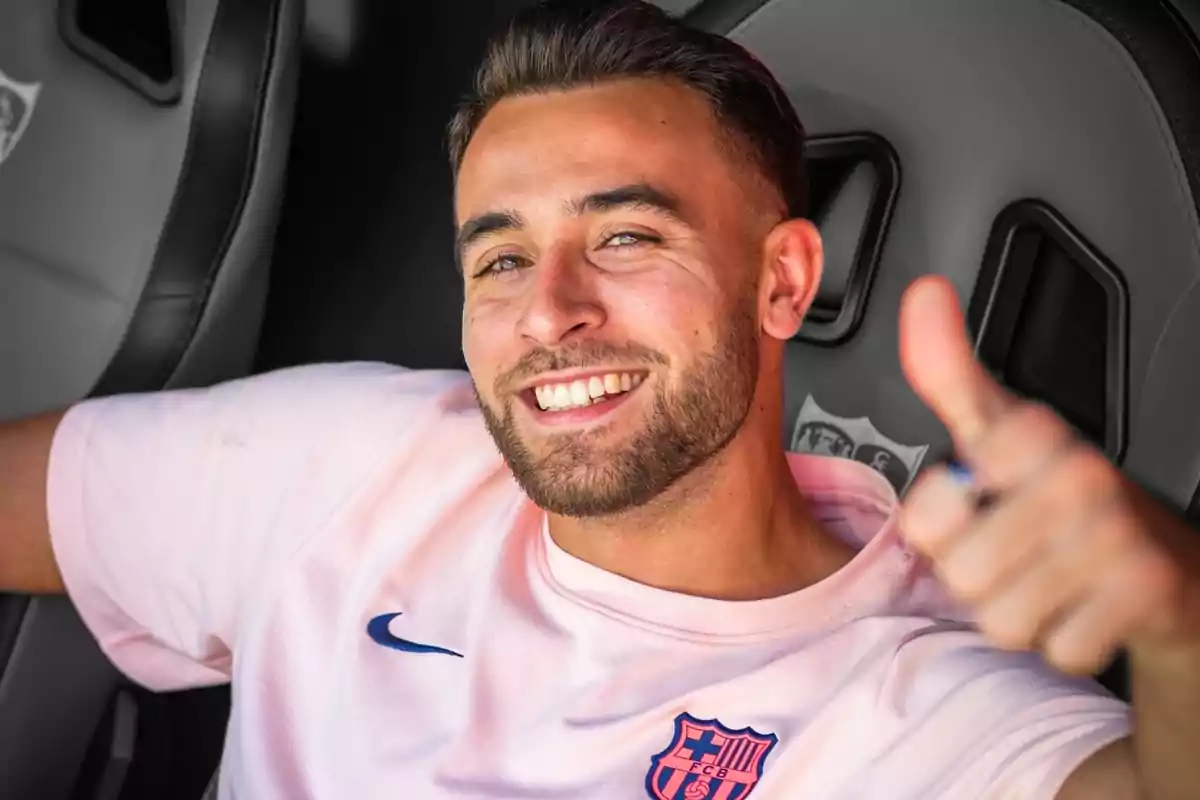 Home jove amb barba somriu i fa un gest de polze amunt mentre porta una samarreta rosa del FC Barcelona