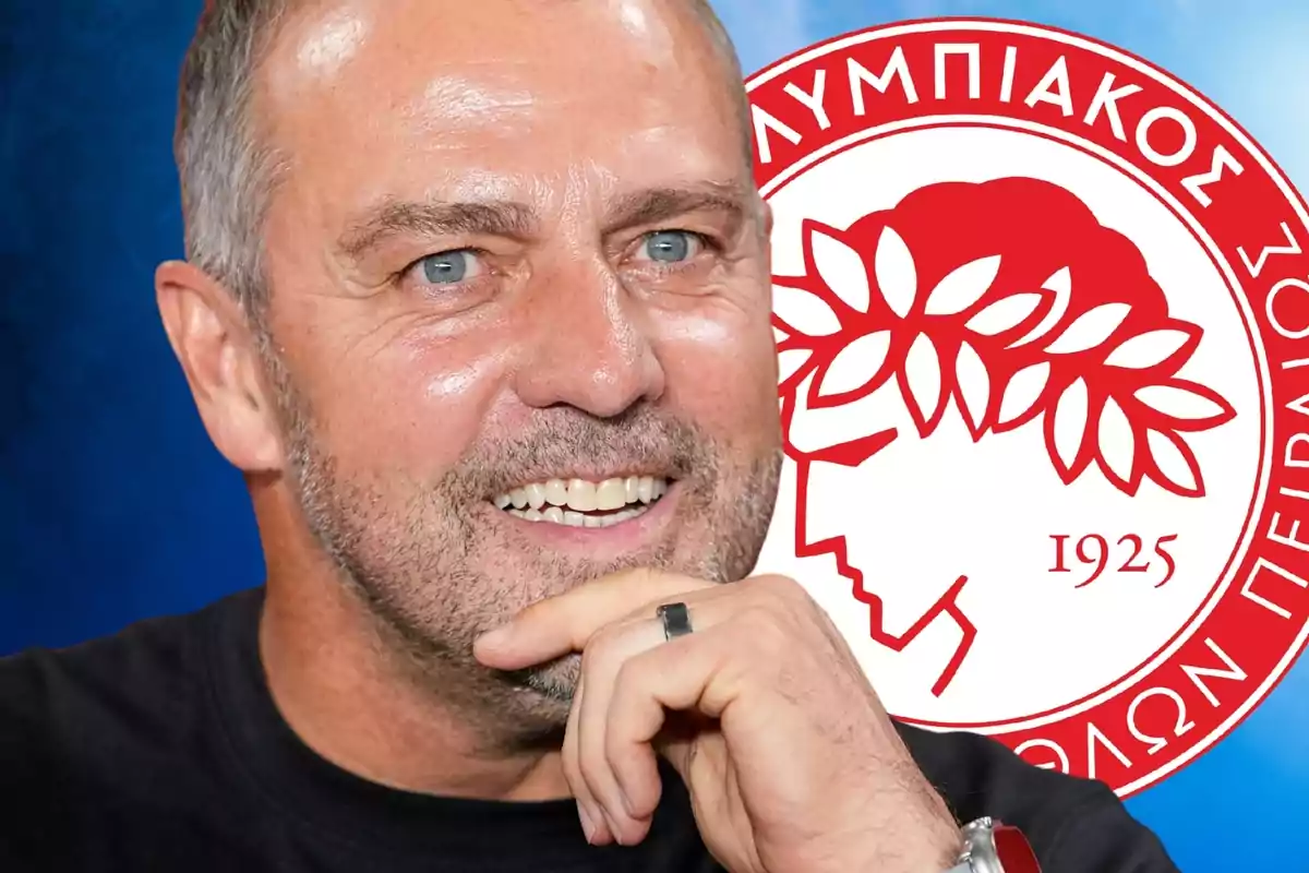 Hombre sonriente con barba frente al escudo del club Olympiacos