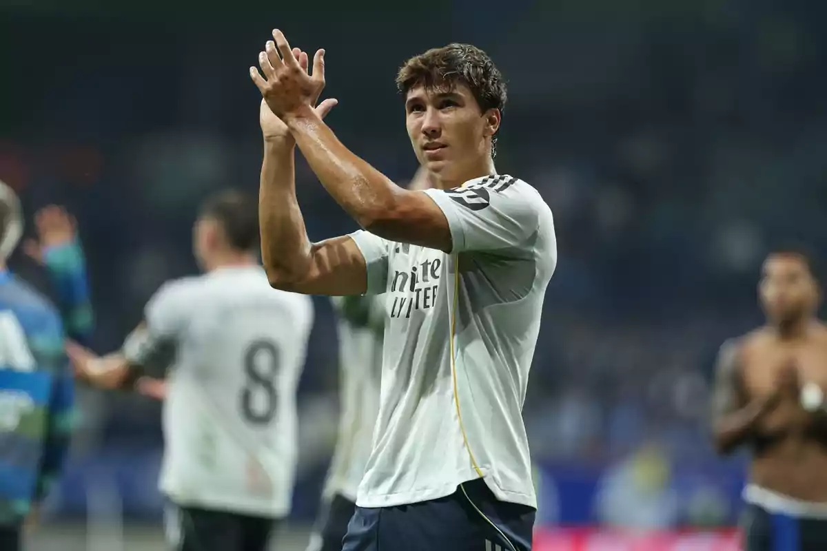 Jugador de fútbol con camiseta blanca aplaudiendo en el campo después de un partido Jugador de fútbol con camiseta blanca aplaudiendo en el campo después de un partido
