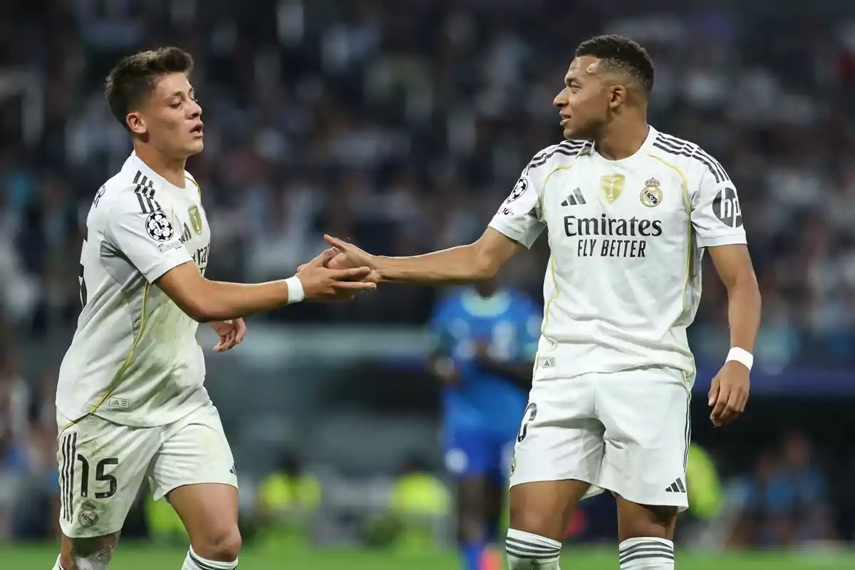 Two Real Madrid players shake hands on the field during a soccer match.