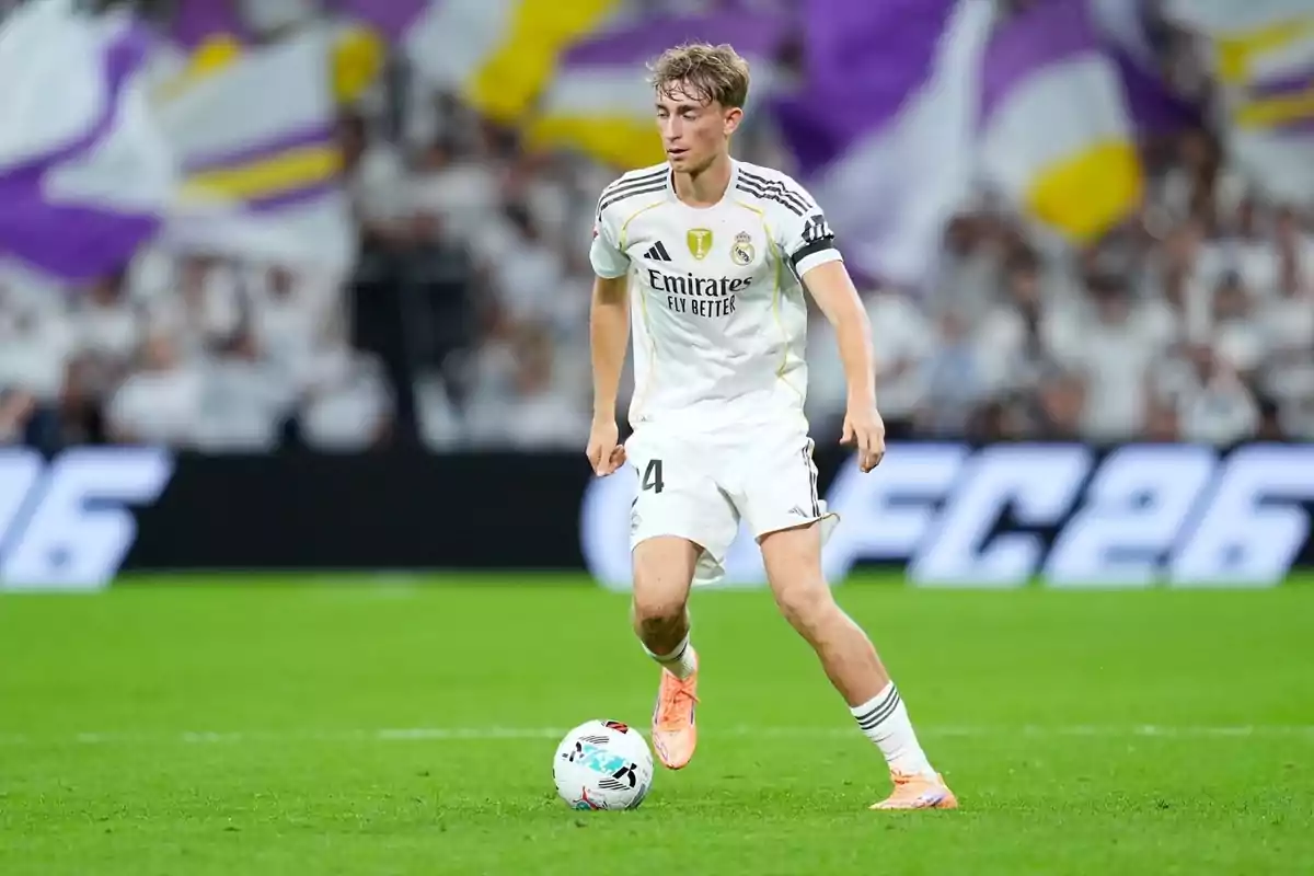 Futbolista del Reial Madrid controlant la pilota durant un partit en un estadi ple d’aficionats