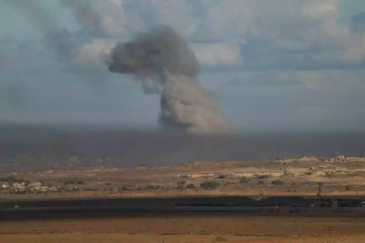 Núvol de fum fosc s’eleva sobre una zona urbana a l’horitzó sota un cel parcialment ennuvolat a Gaza. Núvol de fum fosc s’eleva sobre una zona urbana a l’horitzó sota un cel parcialment ennuvolat a Gaza.