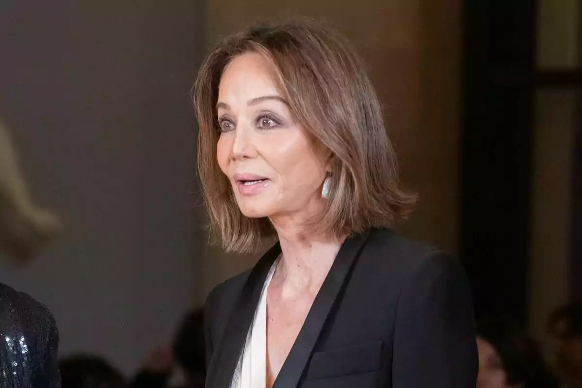 Mujer de cabello castaño corto y liso con saco negro y blusa clara en un evento formal