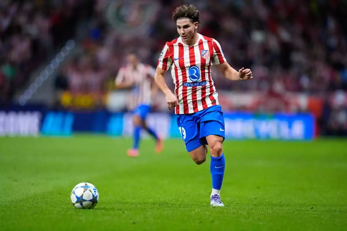 Futbolista del Atlético de Madrid corriendo hacia el balón durante un partido en un estadio lleno de espectadores