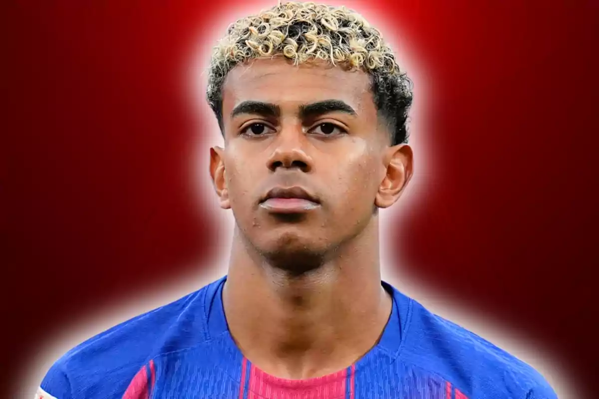 Jove futbolista amb cabell arrissat ros i fosc vestint un uniforme blau amb un fons vermell difuminat