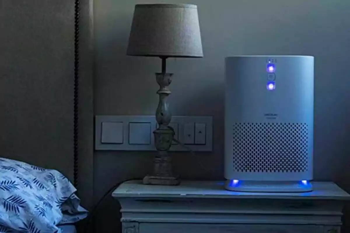 Purificador d’aire encès sobre una taula al costat d’una làmpada en una habitació