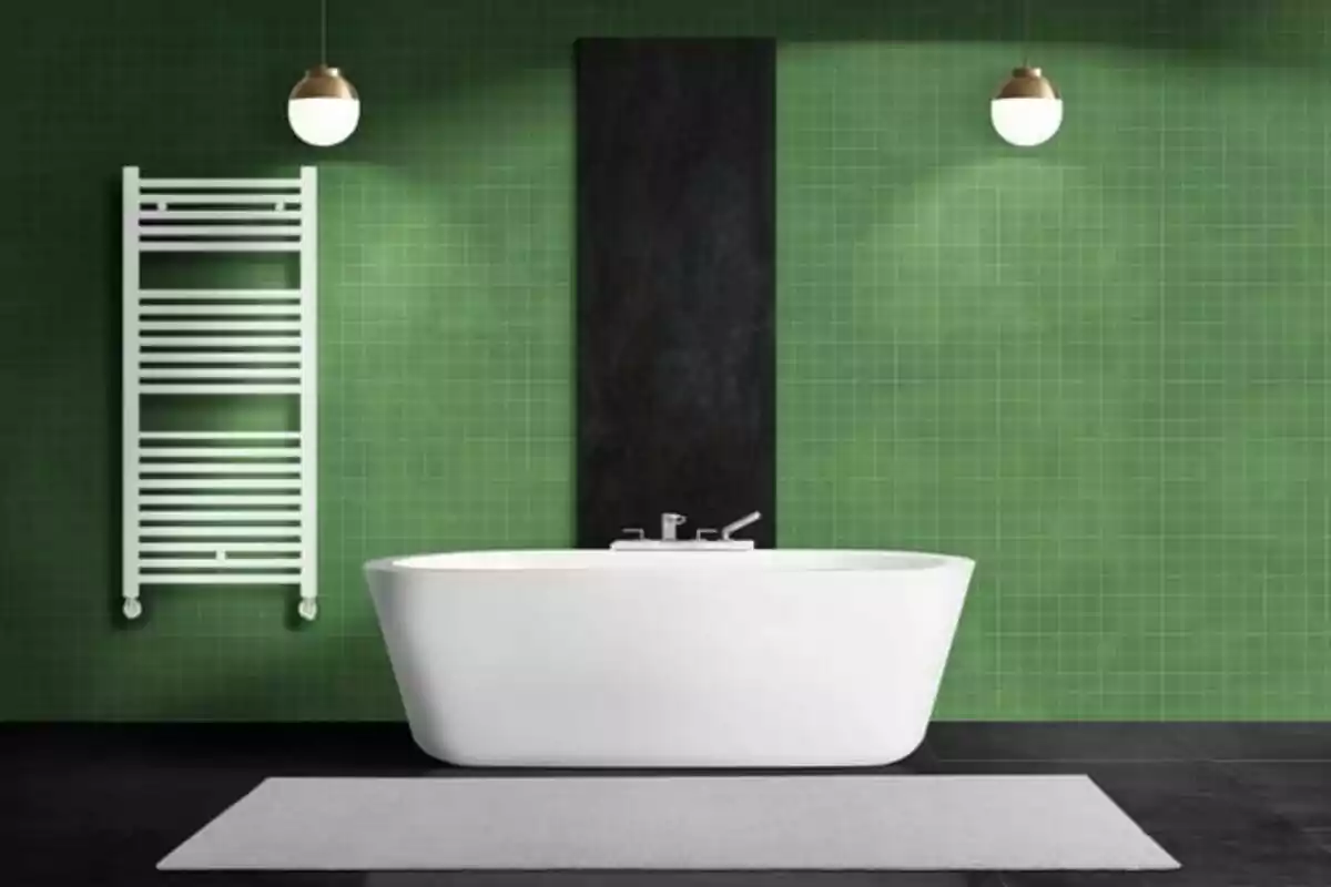 Baño moderno con bañera blanca independiente, pared de azulejos verdes, radiador toallero blanco y dos lámparas colgantes redondas