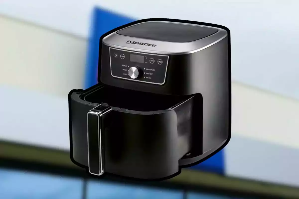Freidora de aire negra SilverCrest con la bandeja abierta sobre un fondo desenfocado. Freidora de aire negra SilverCrest con la bandeja abierta sobre un fondo desenfocado.