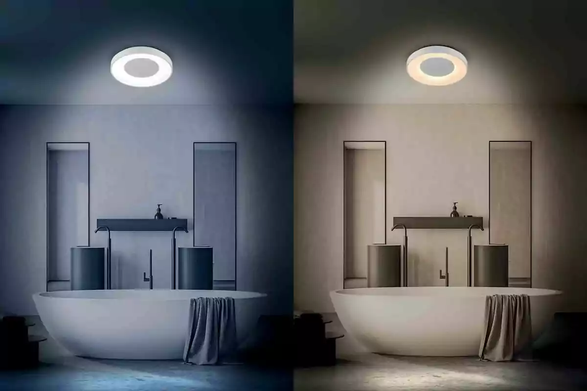 Baño moderno con tina ovalada y toalla, iluminado por una lámpara de techo que muestra dos tipos de luz, una fría a la izquierda y una cálida a la derecha