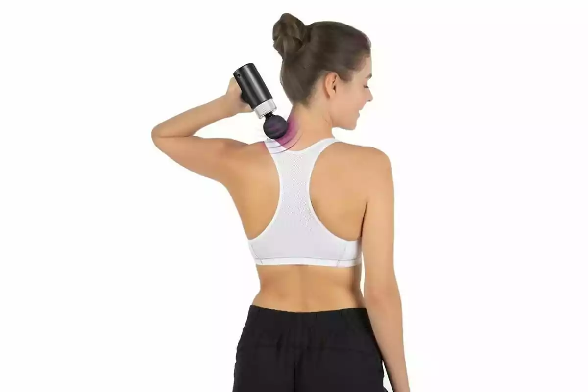 Mujer usando una pistola de masaje en el cuello vestida con ropa deportiva blanca y negra sobre fondo blanco