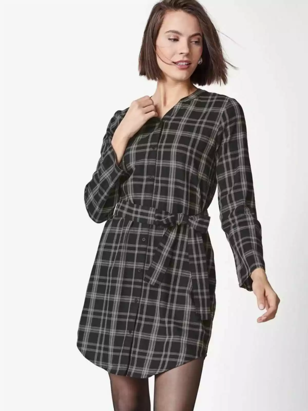 Mujer con cabello corto usando un vestido camisero de manga larga con estampado de cuadros en tonos oscuros y cinturón a juego