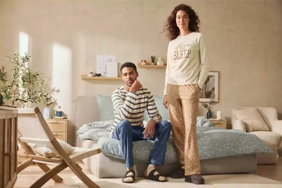 Dues persones amb pijames posen en una habitació acollidora amb llit i decoració minimalista Dues persones amb pijames posen en una habitació acollidora amb llit i decoració minimalista