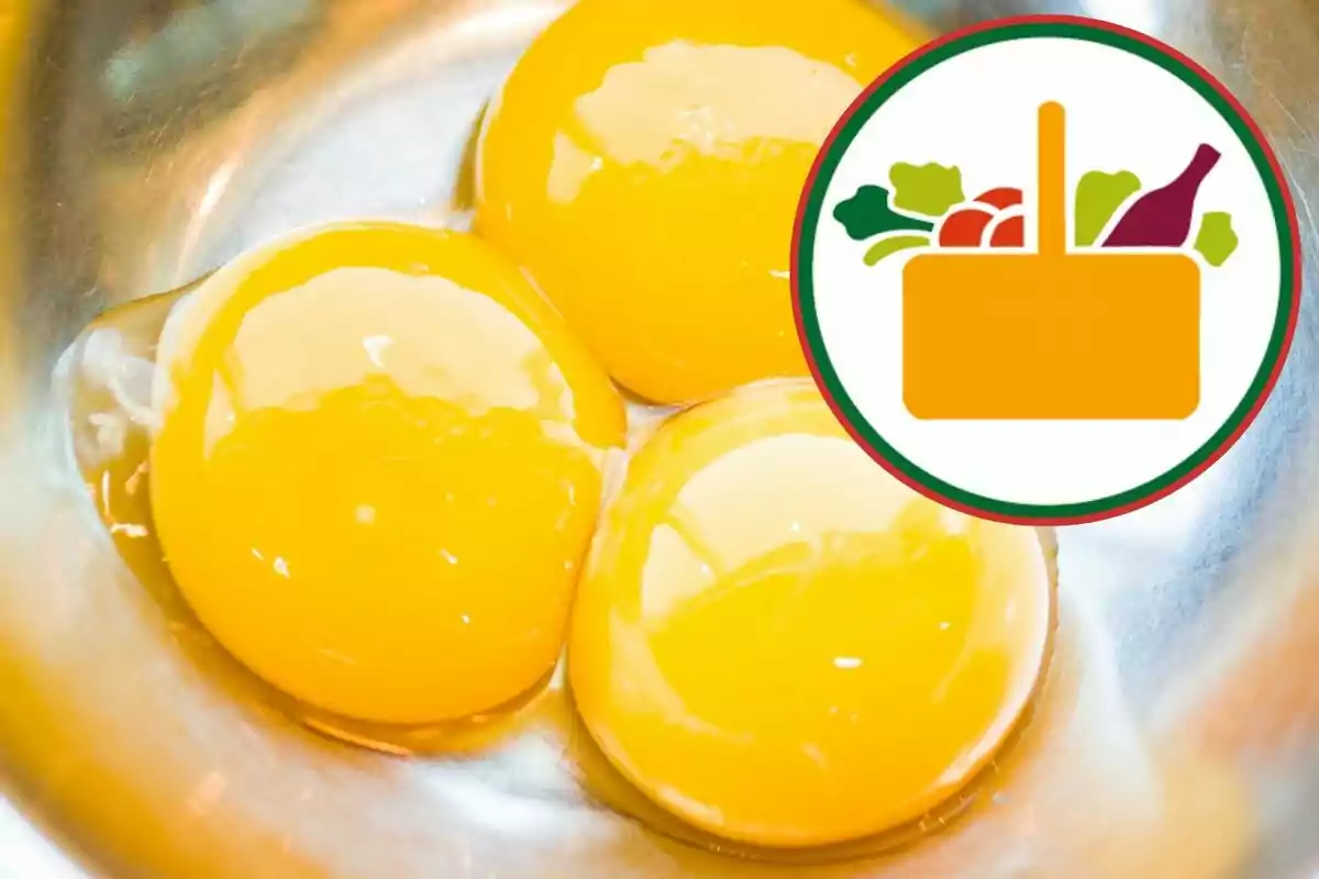 Tres yemas de huevo frescas en un recipiente metálico con un gráfico de canasta de supermercado en la esquina superior derecha