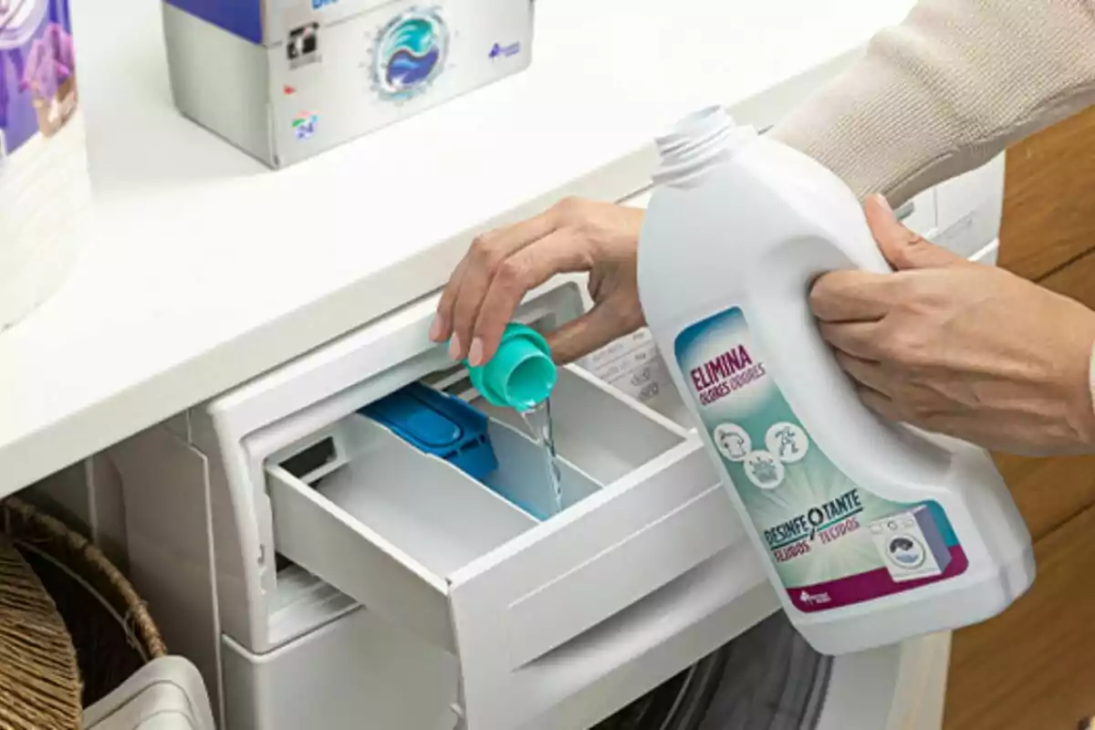 Persona vertiendo detergente líquido en el compartimento de una lavadora. Persona vertiendo detergente líquido en el compartimento de una lavadora.