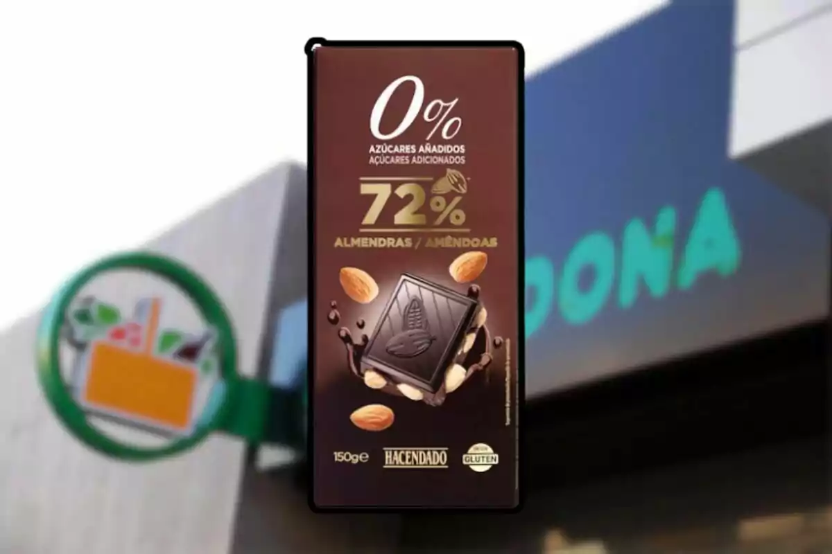 Tableta de chocolate negro con almendras Hacendado sin azúcares añadidos frente a una tienda Mercadona desenfocada