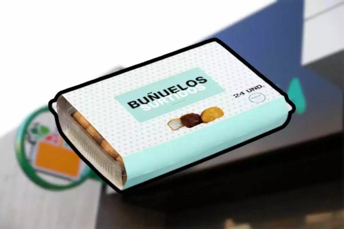 Caja de buñuelos surtidos con empaque azul claro y blanco frente a una tienda