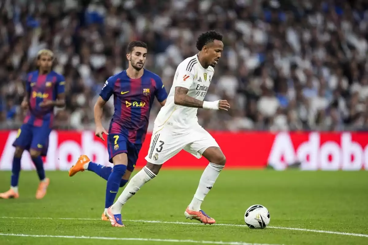 Futbolista del Reial Madrid controla la pilota mentre és perseguit per un jugador del Barcelona durant un partit en un estadi ple d’aficionats