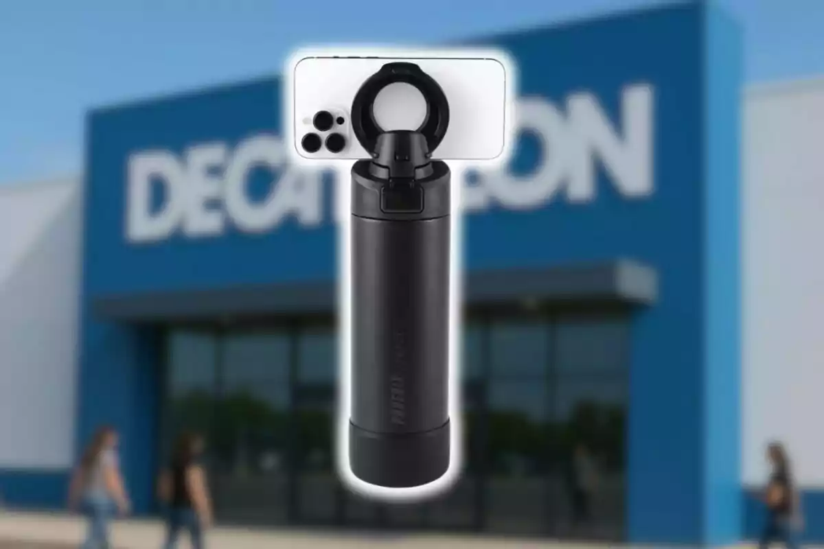 Ampolla negra amb suport per a mòbil davant d’una botiga Decathlon desenfocada.