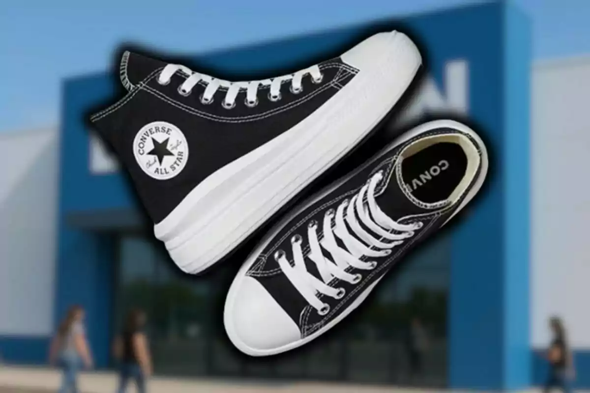 Imatge d’unes sabatilles Converse All Star negres amb sola blanca sobre un fons de botiga difuminat.