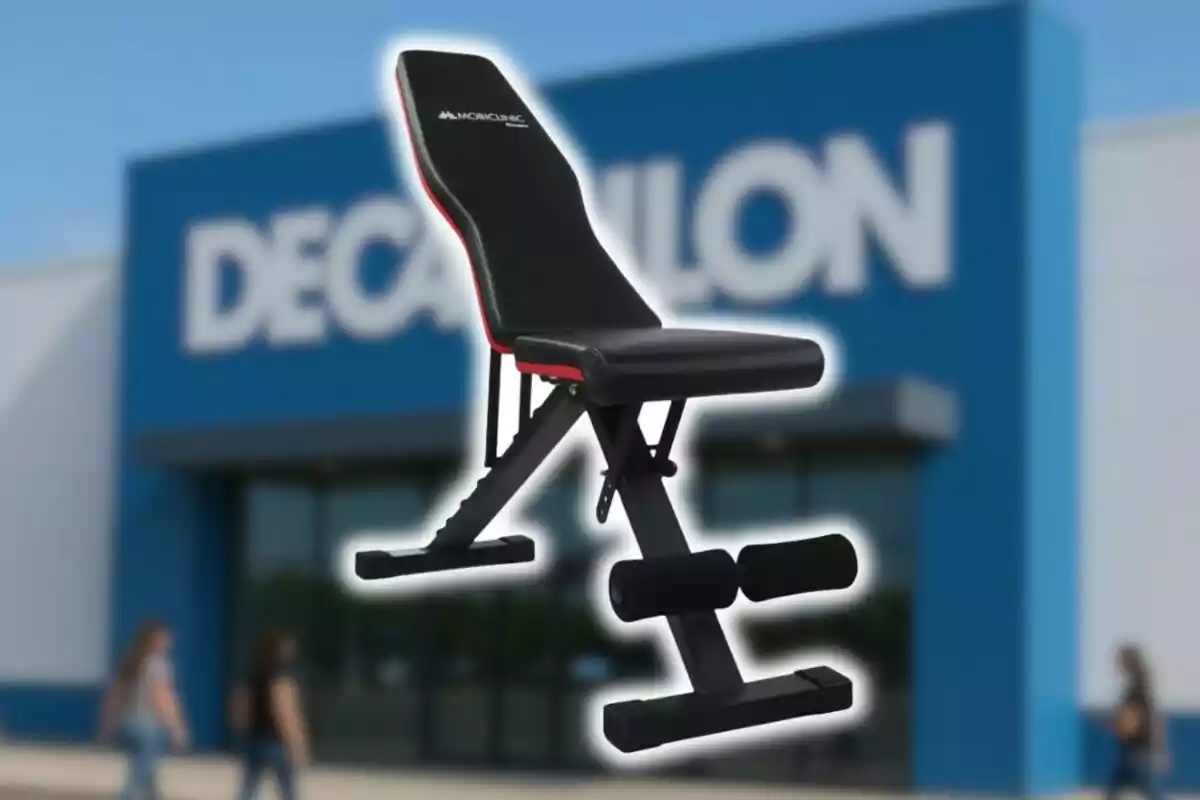 Banc de pesos negre amb detalls vermells davant d’una botiga Decathlon desenfocada.