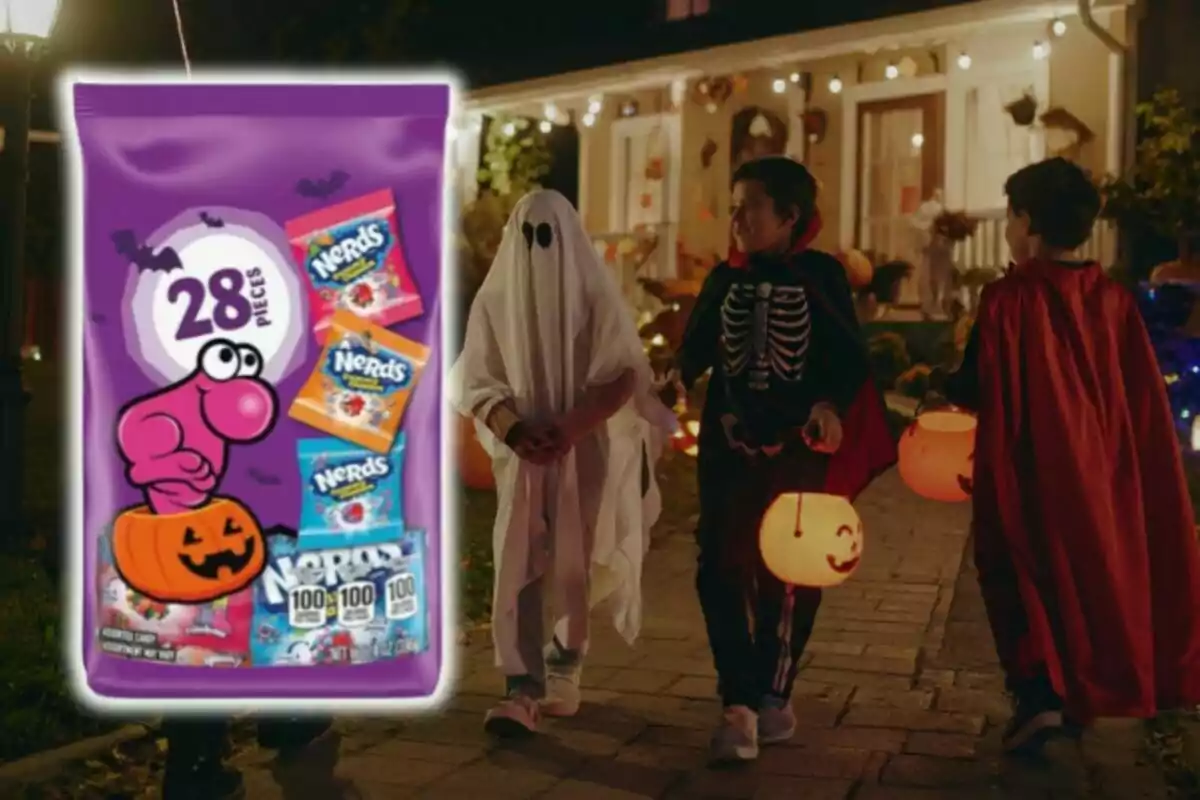 Bolsa de dulces Nerds con 28 piezas de Aldi al frente y tres niños disfrazados de fantasma, esqueleto y vampiro caminando en la noche de Halloween con calabazas para pedir dulces.