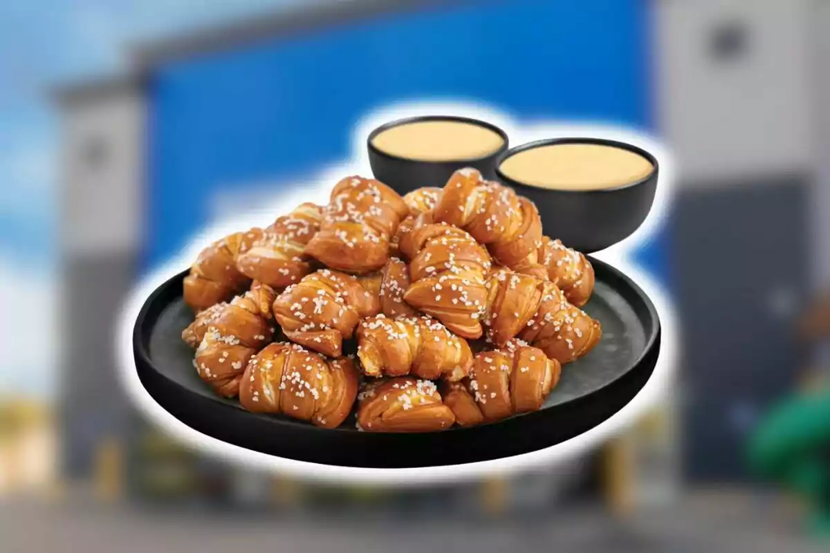 Bandeja de pretzel bites cubiertos con sal gruesa acompañados de dos recipientes con salsa de queso.