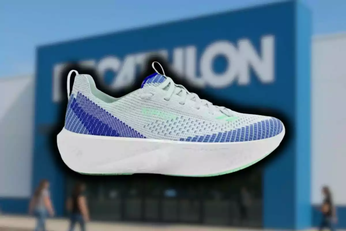 Sabatilla esportiva blanca amb detalls blaus i verds davant d’una botiga de Decathlon desenfocada.