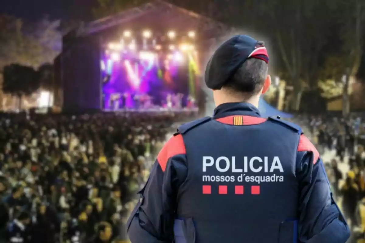 Agente de los Mossos d'Esquadra vigilando un concierto al aire libre con una multitud de personas y luces en el escenario
