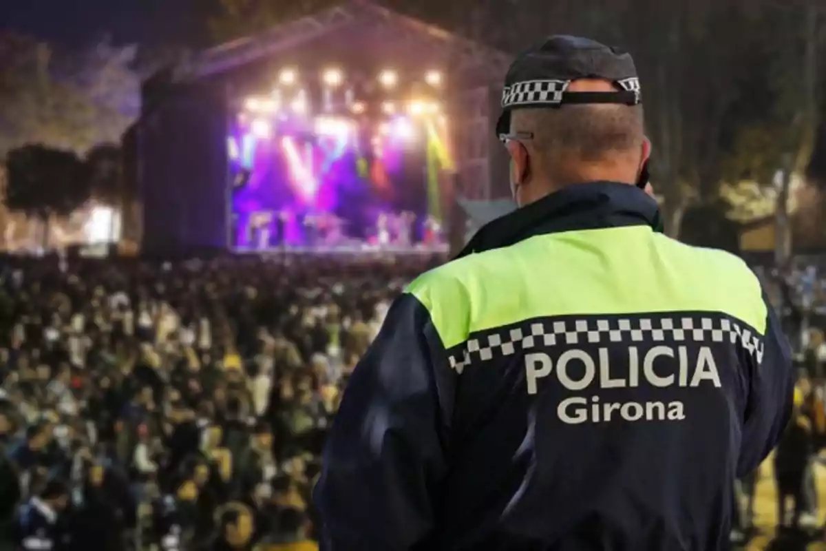 Agente de policía de Girona vigilando un concierto al aire libre con una multitud de personas frente al escenario iluminado