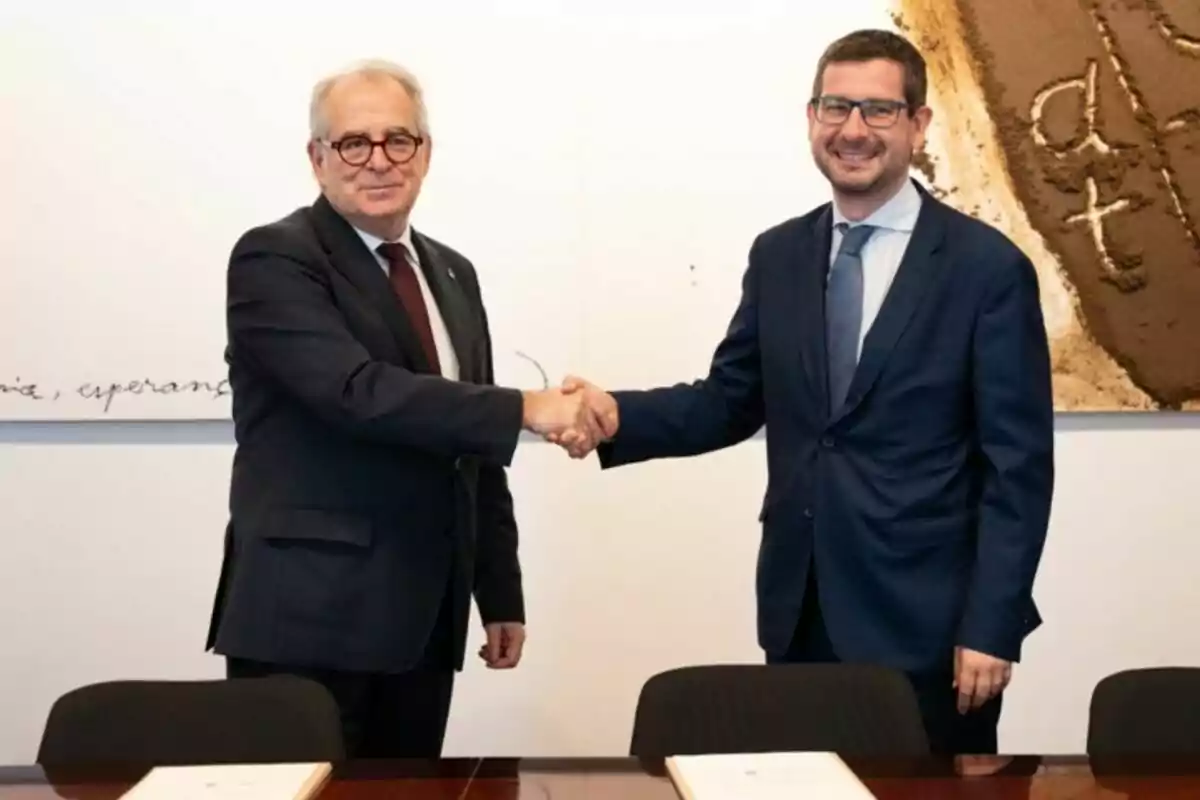 Dos hombres de traje se dan la mano y sonríen en una sala de reuniones