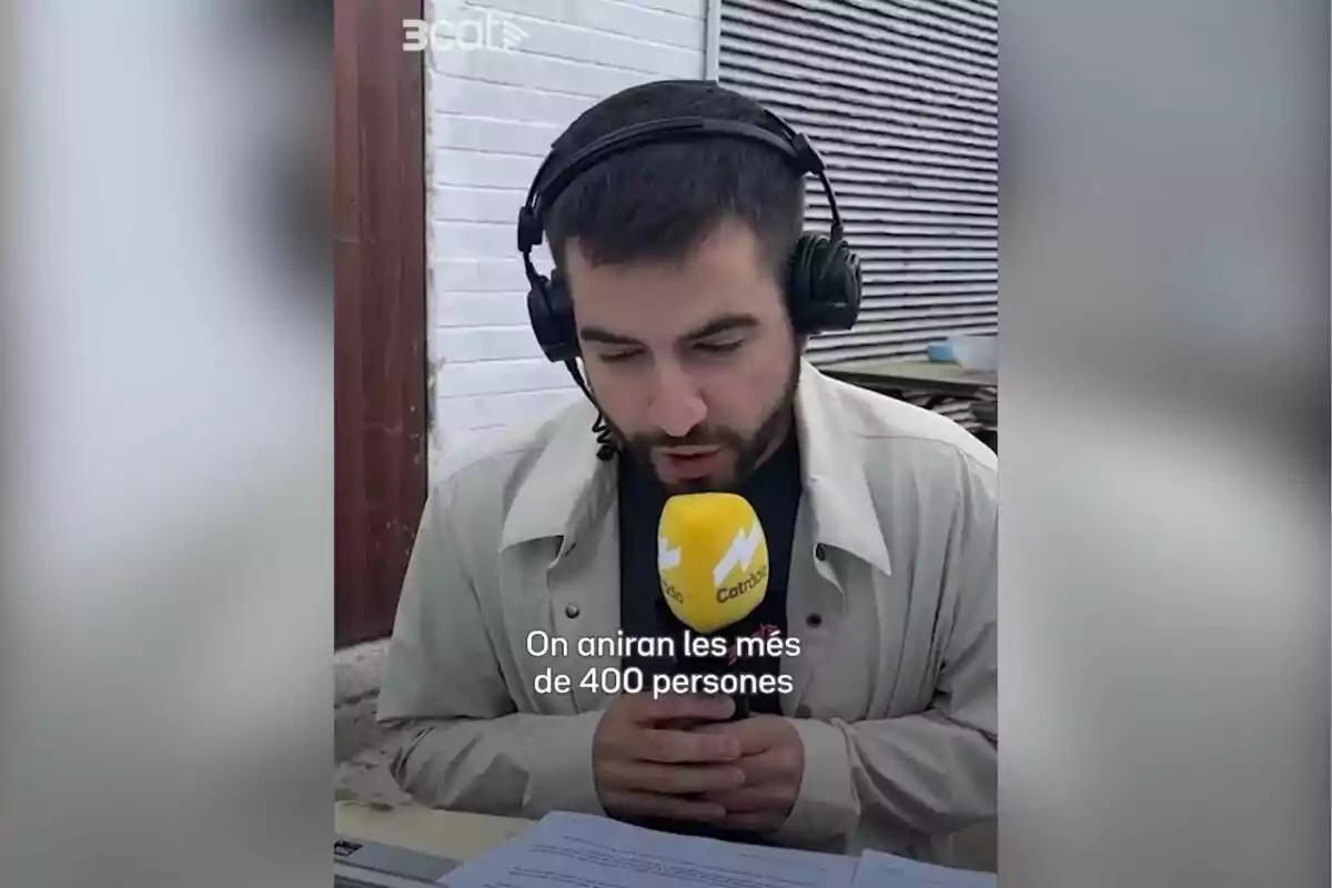 Hombre con auriculares y micrófono amarillo de radio hablando frente a unos papeles con texto en catalán sobre la imagen
