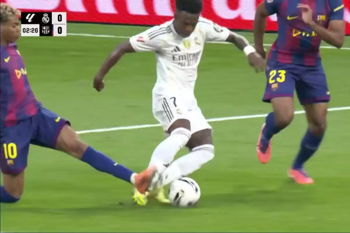 Un jugador del Reial Madrid intenta controlar la pilota mentre dos jugadors del Barcelona intenten prendre-li la pilota durant un partit de futbol.