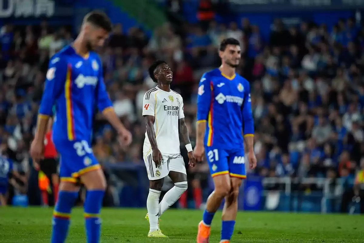 Un jugador del Reial Madrid amb un gest de frustració al camp envoltat de dos futbolistes del Getafe durant un partit de futbol Un jugador del Reial Madrid amb un gest de frustració al camp envoltat de dos futbolistes del Getafe durant un partit de futbol