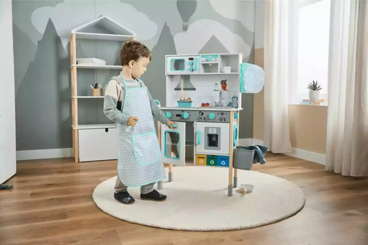 Nen petit jugant amb una cuina de joguina en una habitació infantil decorada amb prestatgeria i catifa rodona.
