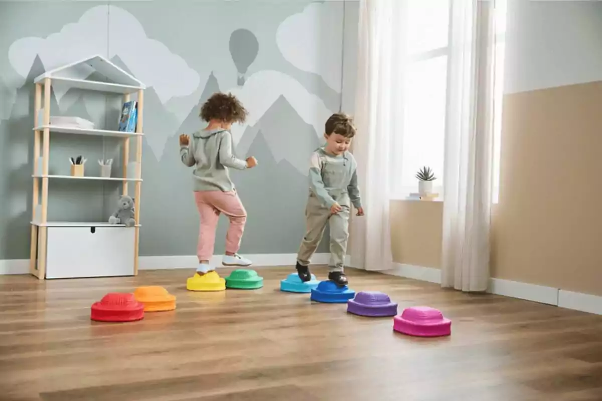 Dos niños juegan en una habitación saltando sobre piezas de colores en el suelo Dos niños juegan en una habitación saltando sobre piezas de colores en el suelo