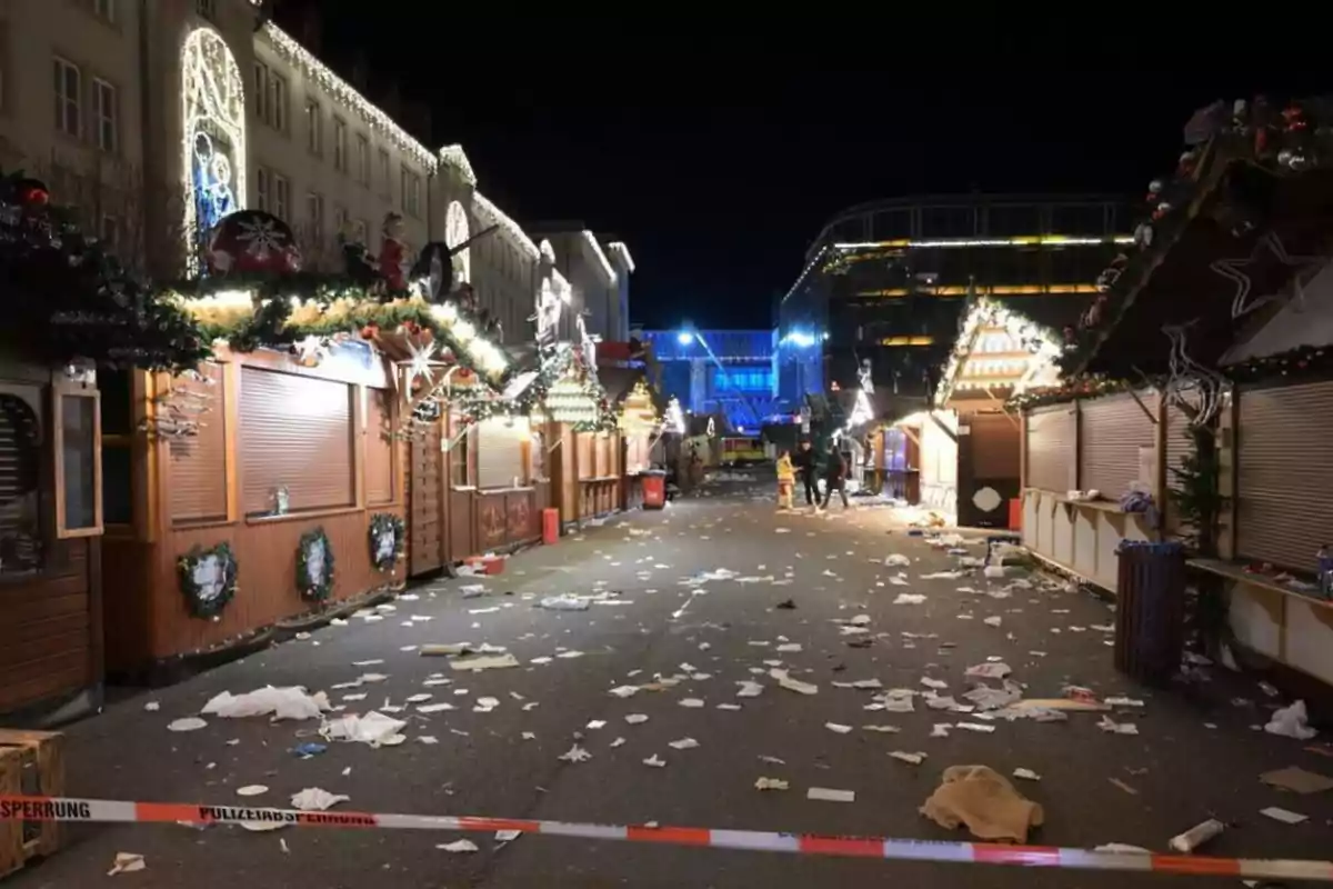 Carrer d’un mercat de Nadal a la nit amb parades tancades, llums decoratives i escombraries escampades a terra