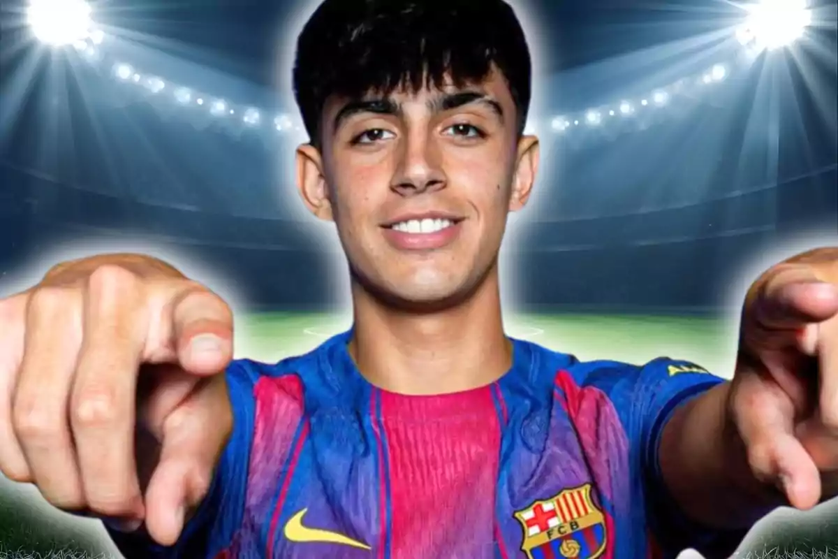 Jove amb samarreta del Barcelona somriu i assenyala cap a la càmera en un estadi il·luminat