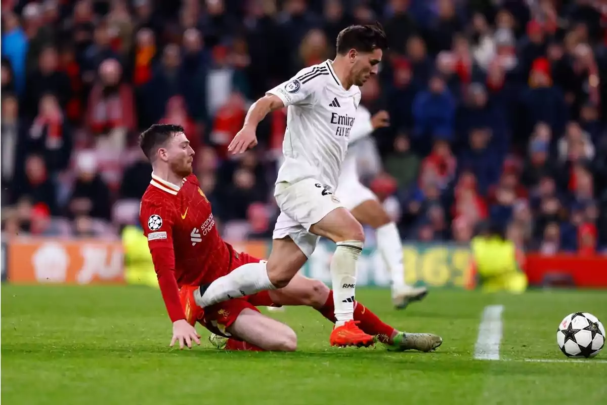 Un jugador del Liverpool fa una entrada per treure la pilota a un jugador del Reial Madrid durant un partit de futbol.