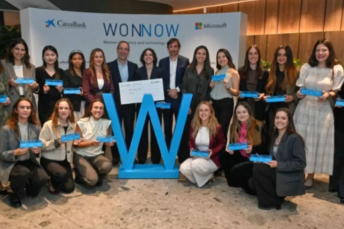 Grup de dones i homes posant en un esdeveniment de lliurament de premis amb un gran símbol de la lletra W blava i un xec, amb logotips de CaixaBank i Microsoft al fons