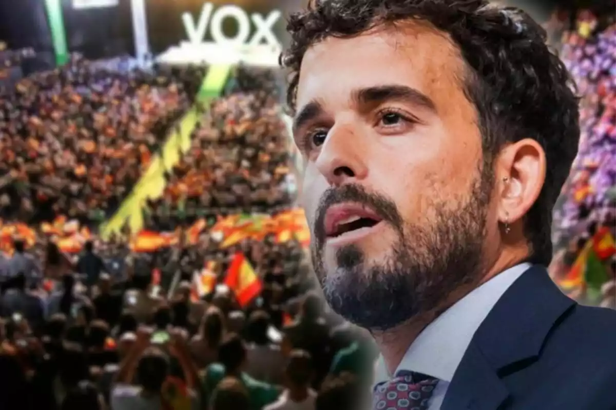 Hombre de barba en primer plano con fondo de multitud en un mitin político con banderas de España y el logo de VOX al fondo