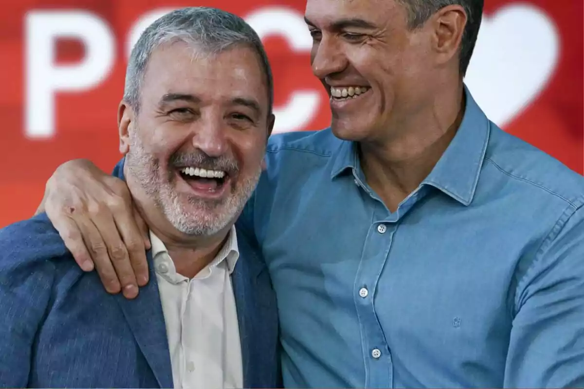 Dos hombres sonríen y se abrazan en un ambiente alegre con un fondo rojo desenfocado