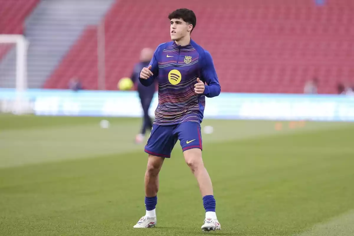 Futbolista del FC Barcelona escalfant al camp abans d’un partit amb l’uniforme d’entrenament blau i de fons grades vermelles Futbolista del FC Barcelona escalfant al camp abans d’un partit amb l’uniforme d’entrenament blau i de fons grades vermelles