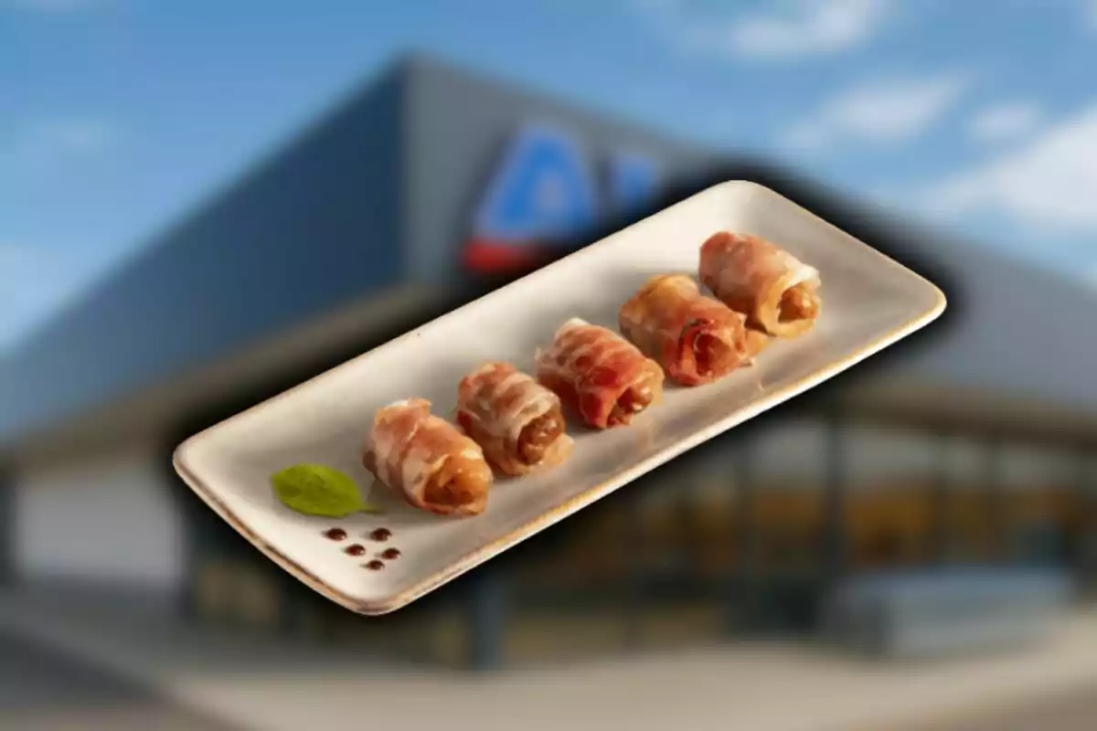 Safata rectangular amb quatre rotllets embolicats amb cansalada i una fulla verda de decoració al fons d’un edifici desenfocat d’Aldi. Safata rectangular amb quatre rotllets embolicats amb cansalada i una fulla verda de decoració al fons d’un edifici desenfocat d’Aldi.