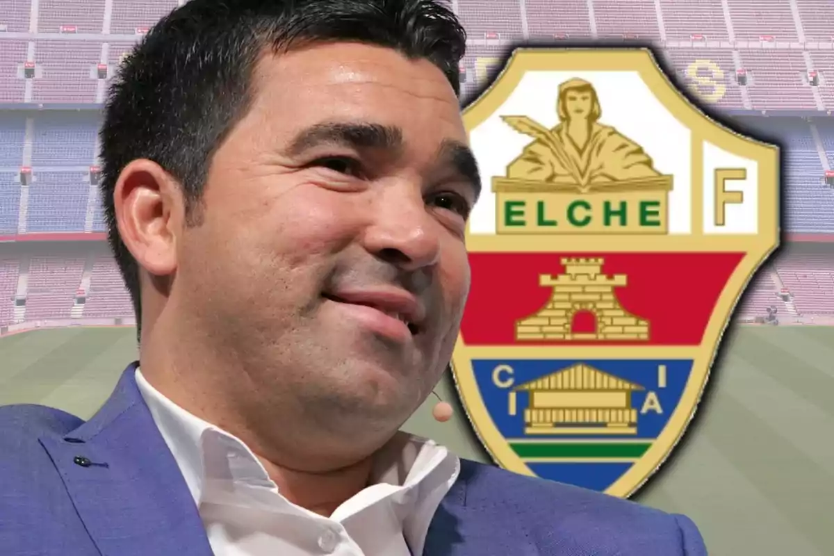 Hombre sonriente con saco azul frente al escudo del Elche CF en un estadio de fútbol