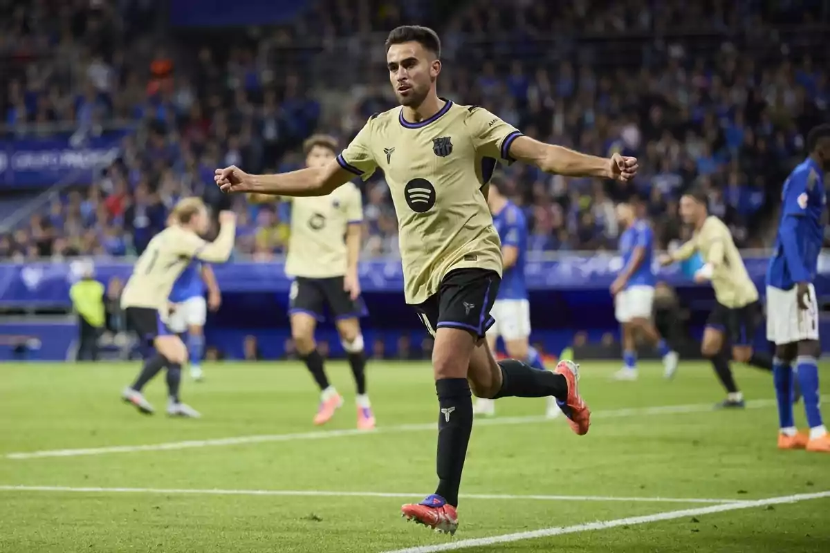 Futbolista celebrant un gol amb els braços estesos durant un partit en un estadi ple d’espectadors