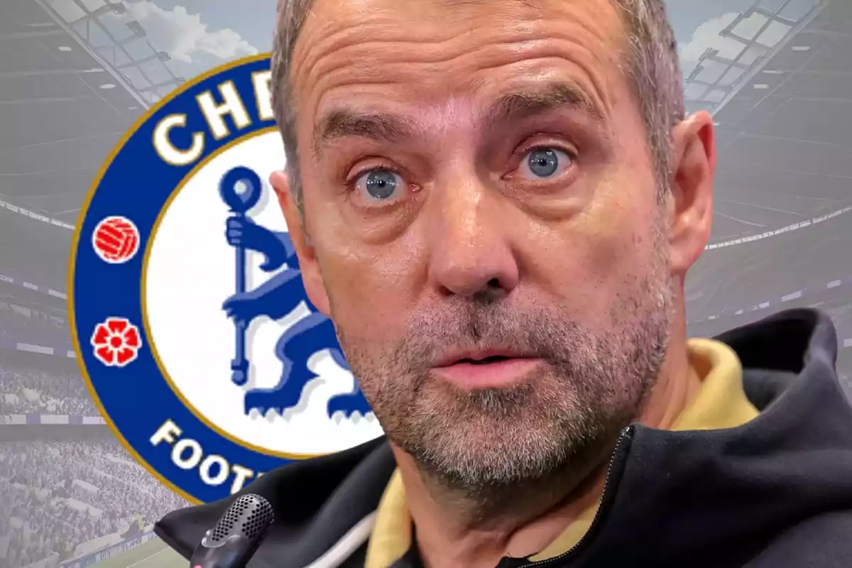 Hombre de mediana edad con barba y expresión seria frente al escudo del Chelsea en un estadio de fútbol.