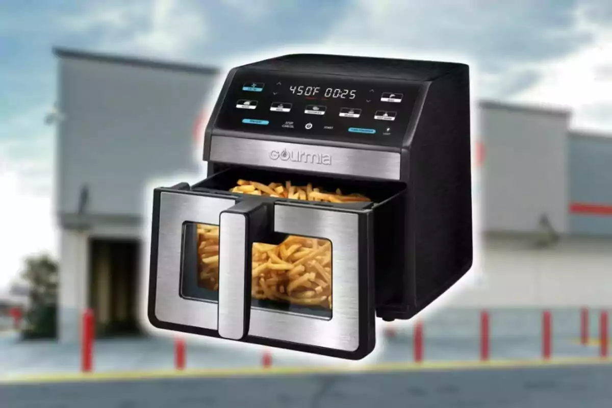 Black and silver air fryer from Costco with French fries inside in front of a blurred building.