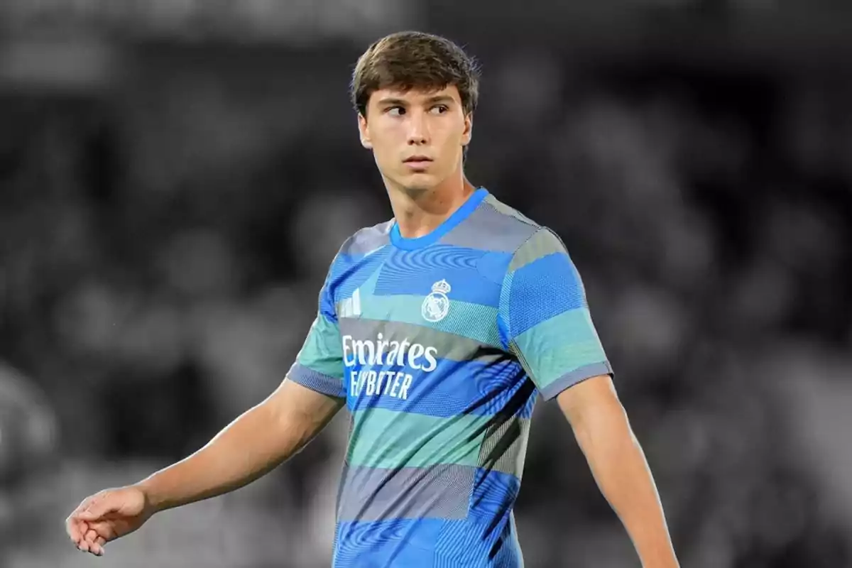 Jugador de futbol amb uniforme blau i verd del Reial Madrid en un estadi Jugador de futbol amb uniforme blau i verd del Reial Madrid en un estadi